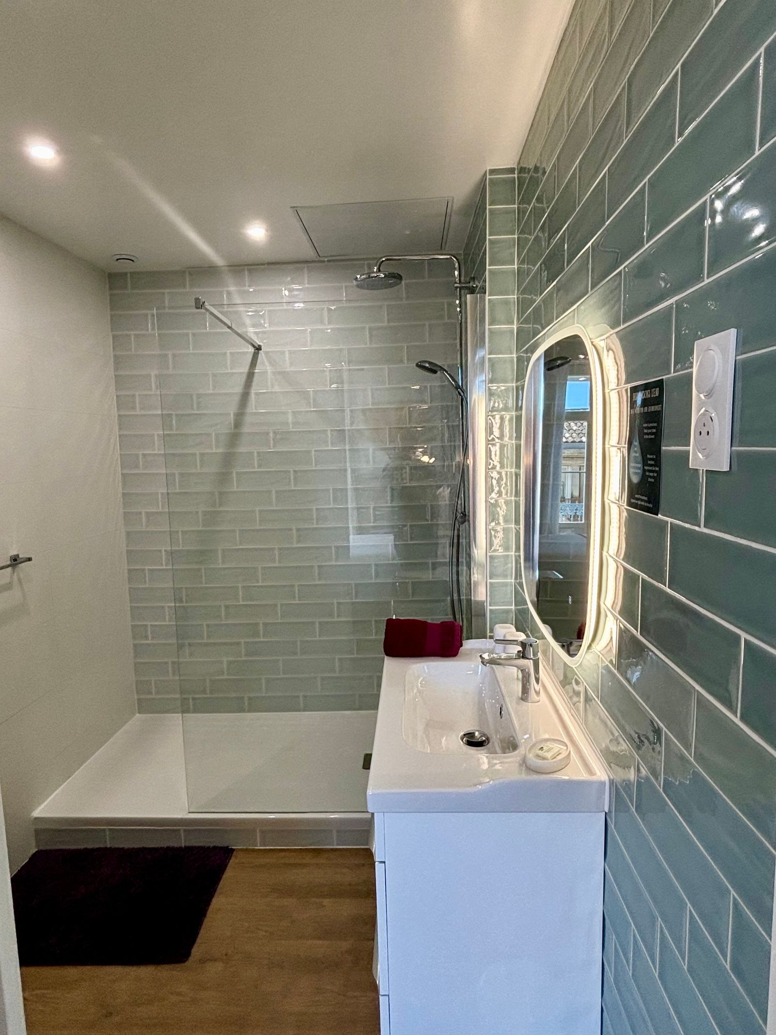 Salle de bain avec douche à l'italienne, un lavabo et un mirroir avec éclairage